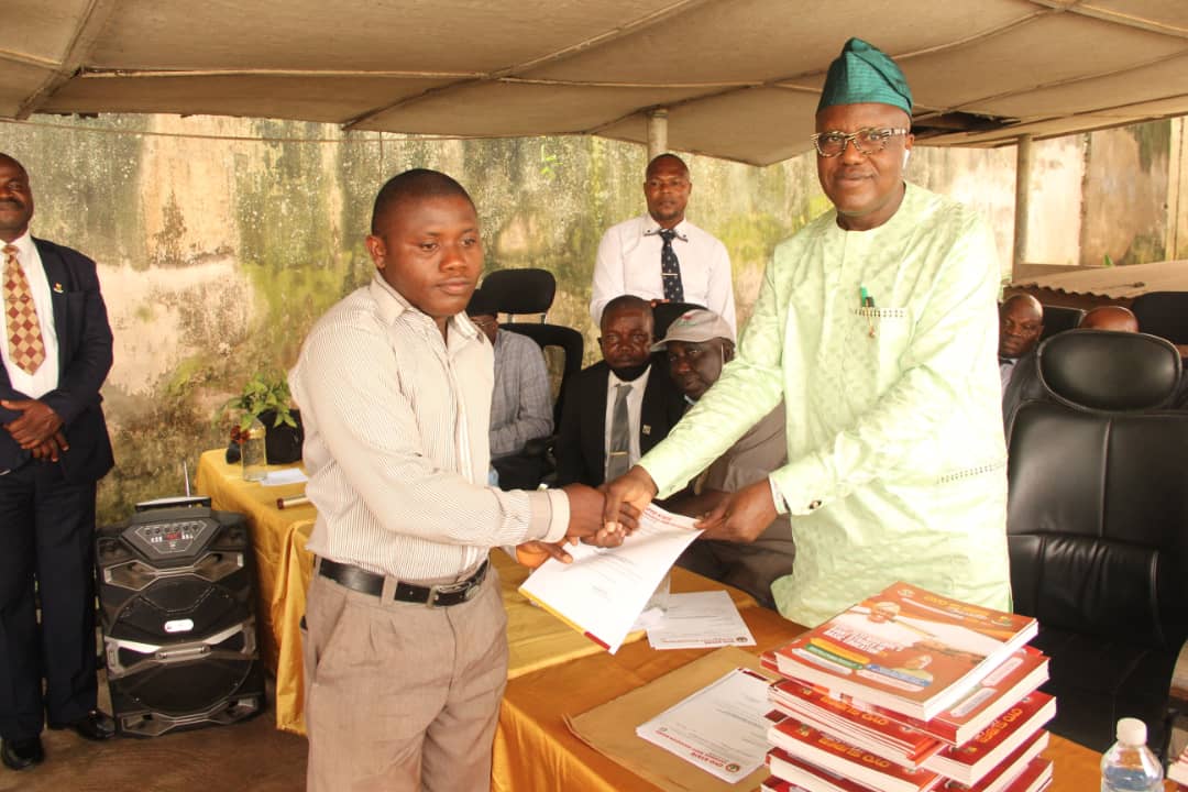 Dr. Adeniran presenting promotion letters to a teacher